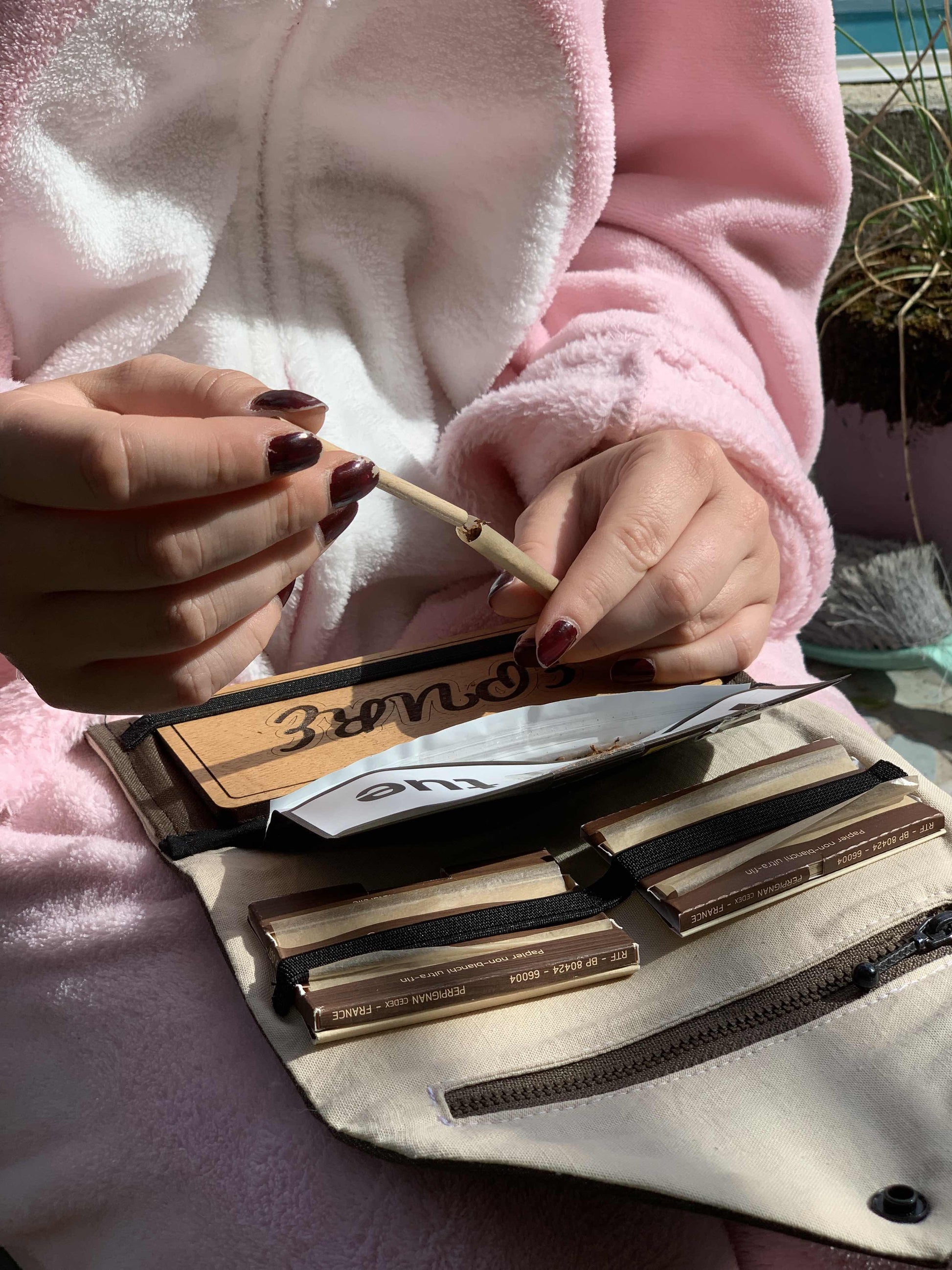 Tasser une cigarette avec la baguette de roulage intégrée à la blague à tabac.